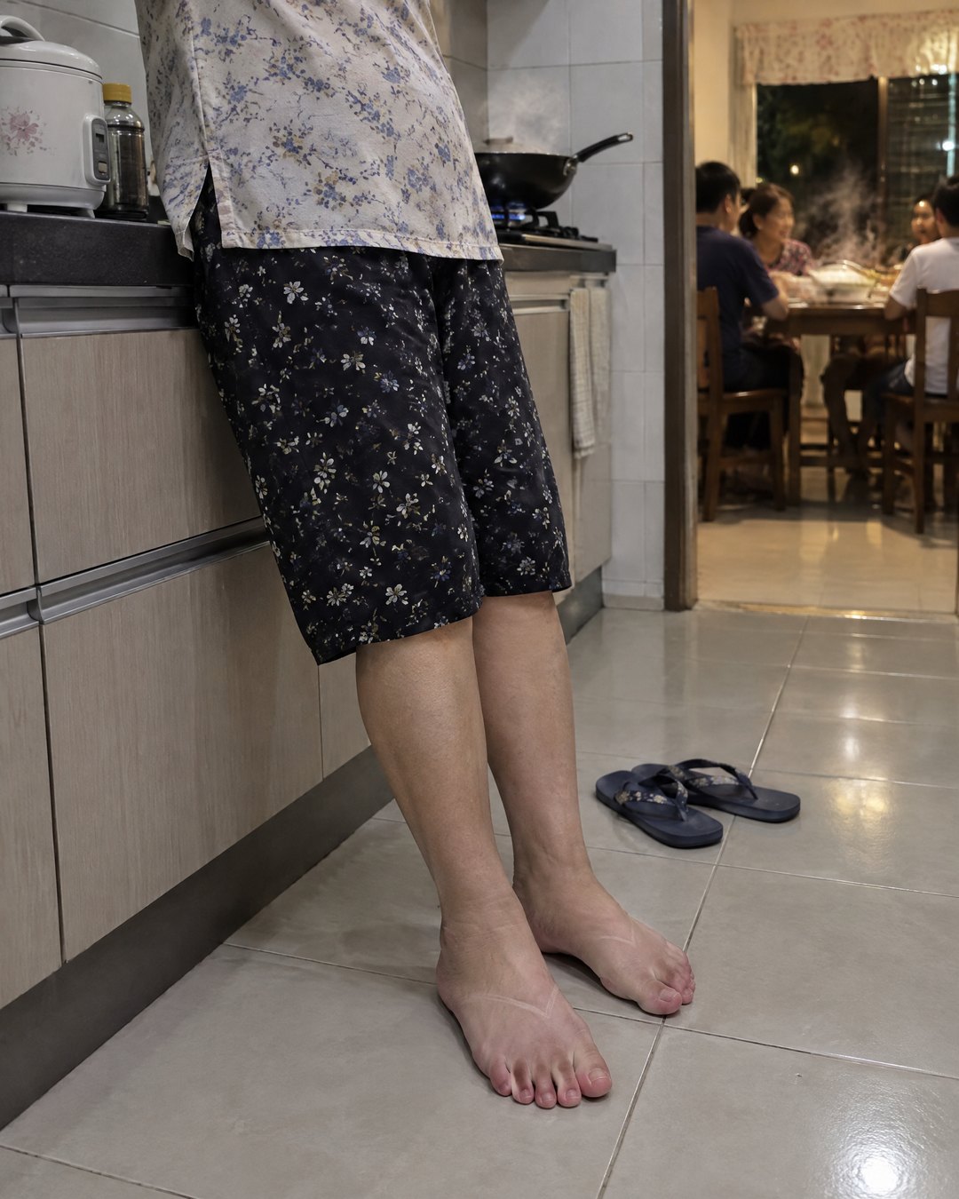 煮完饭,靠在灶台边,拖鞋踢在一旁,脚背上有拖鞋带子压出的印子